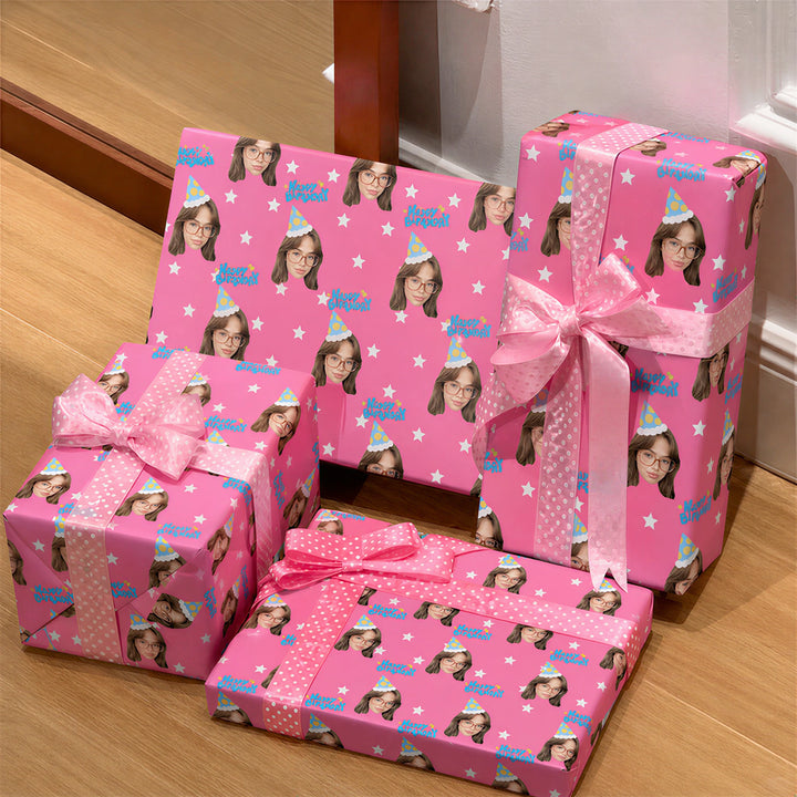 Four gift boxes wrapped in bright pink paper with a repeating cartoon girl pattern, tied with pink ribbons and bows, arranged on a wooden floor indoors.